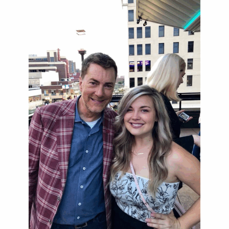 Radio host Dave Ryan in a red plaid sport coat and chambray shirt on a rooftop with Fallon.