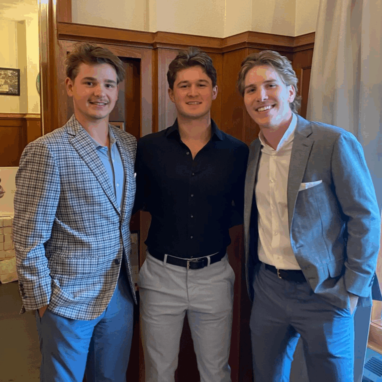 Three young men in custom J.Hilburn outfits, smiling at an award banquet celebration.